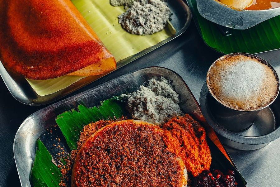 A South Indian breakfast on steel trays: a crisp folded dosa, a podi-topped idli with chutneys, and a filter coffee. Illustrative photograph.